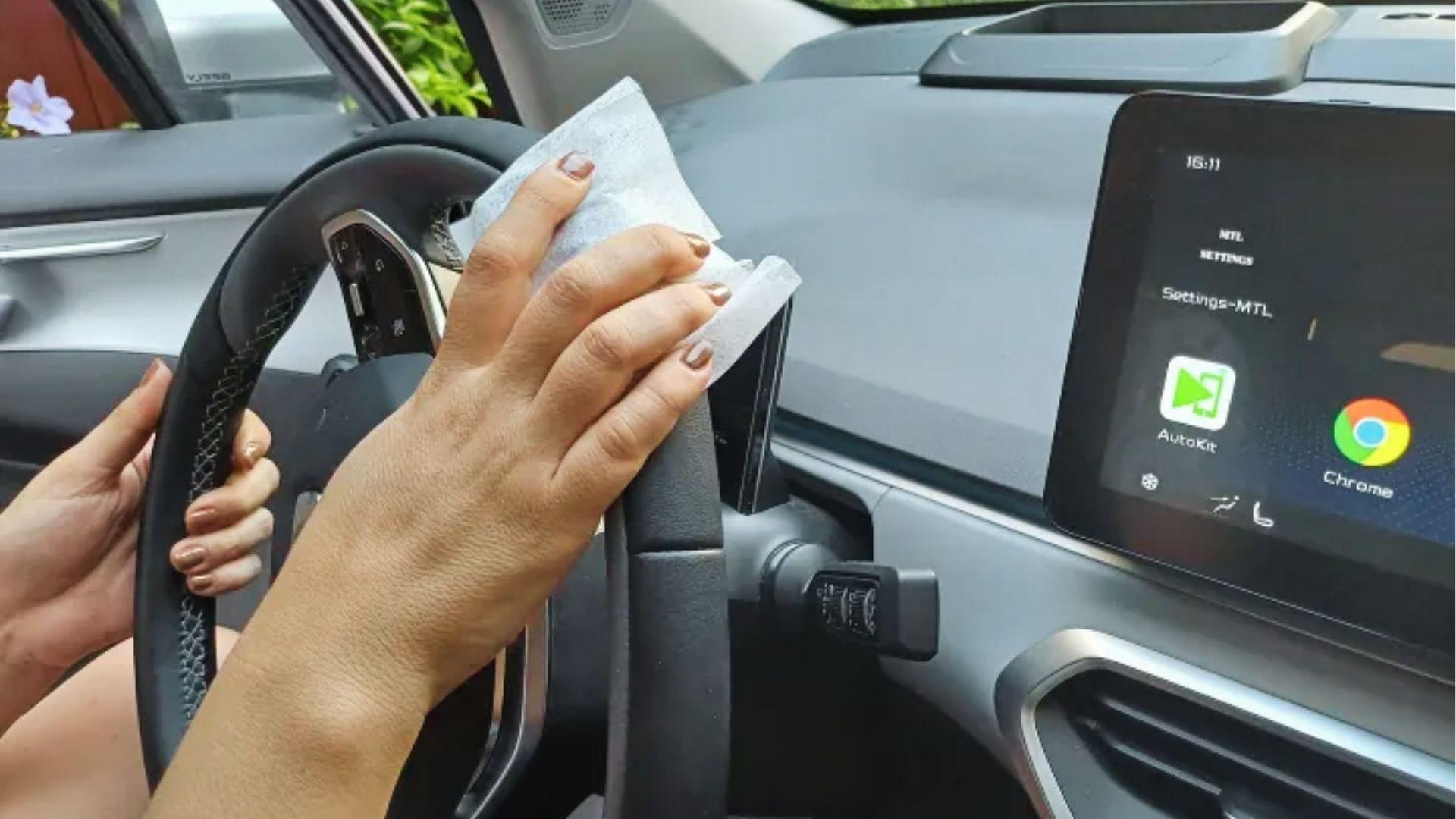Person using cleaning wipes on car steering wheel to remove weed odor naturally