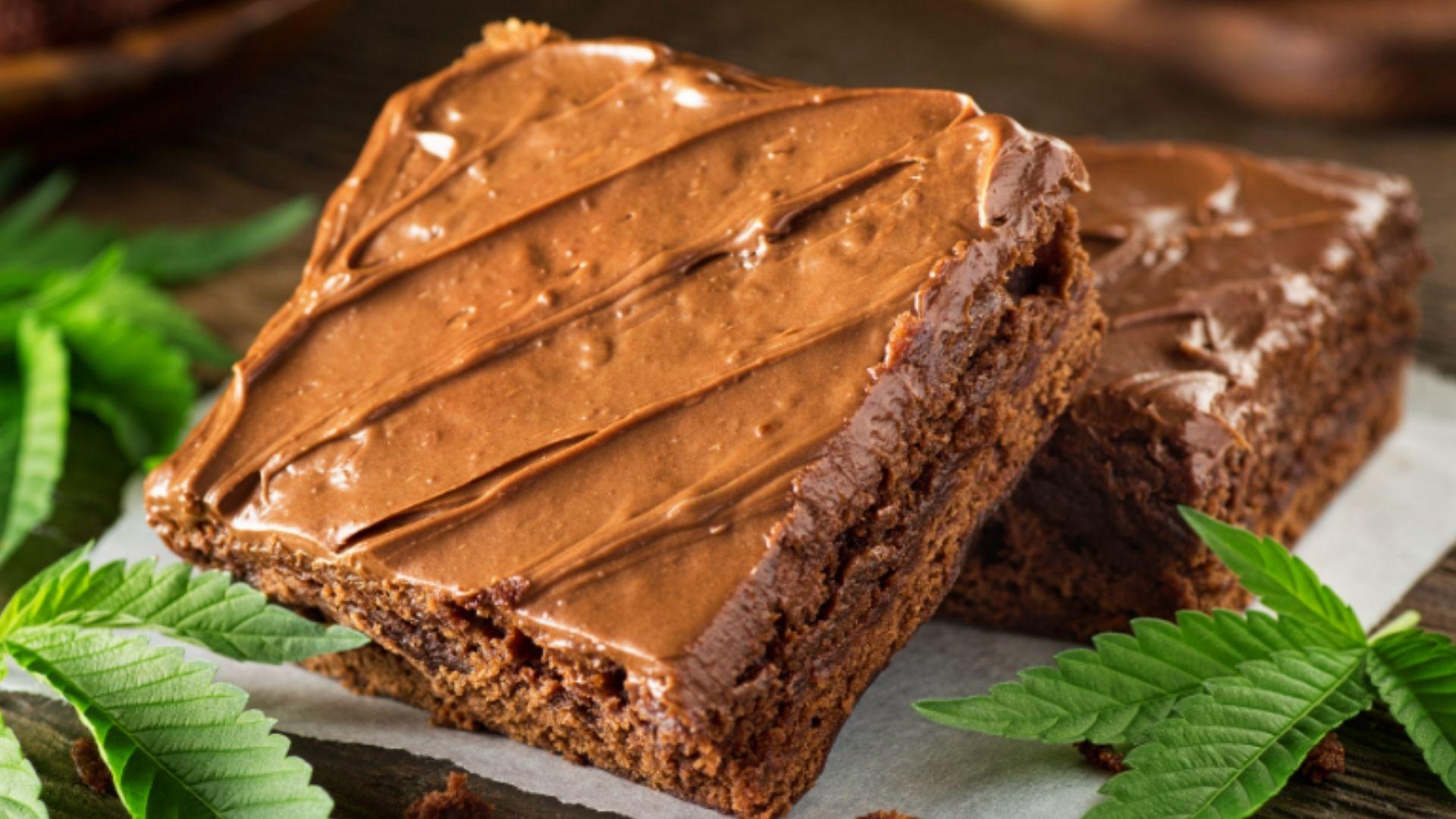 Rich chocolate cannabis brownies with thick frosting and fresh leaves on parchment paper for easy dessert recipes