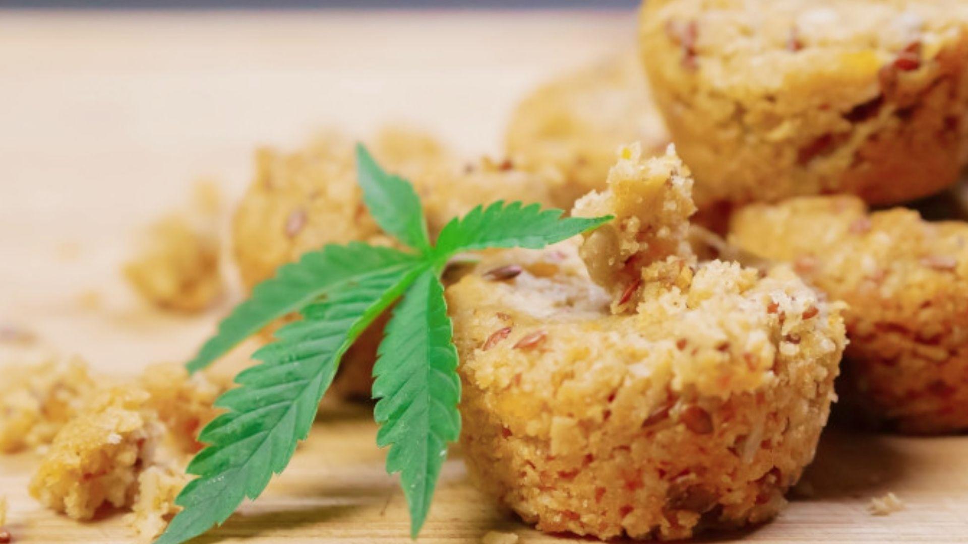 Golden cannabis infused muffins with seeds and fresh leaf garnish on wood board for easy baked edibles