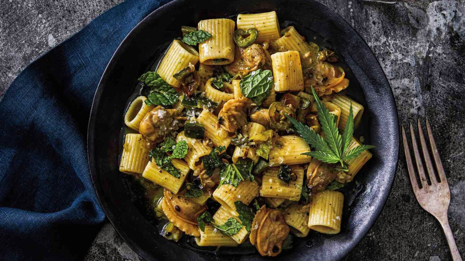 Rigatoni cannabis pasta with herbs and clam sauce in black bowl for savory infused dinner recipes