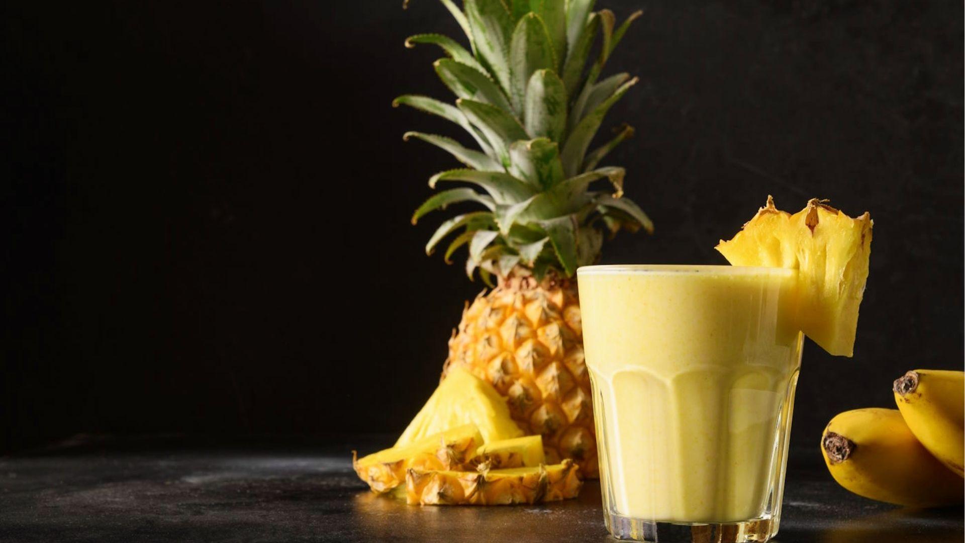 Creamy pineapple cannabis smoothie in glass with fresh pineapple and banana on black background for easy edibles