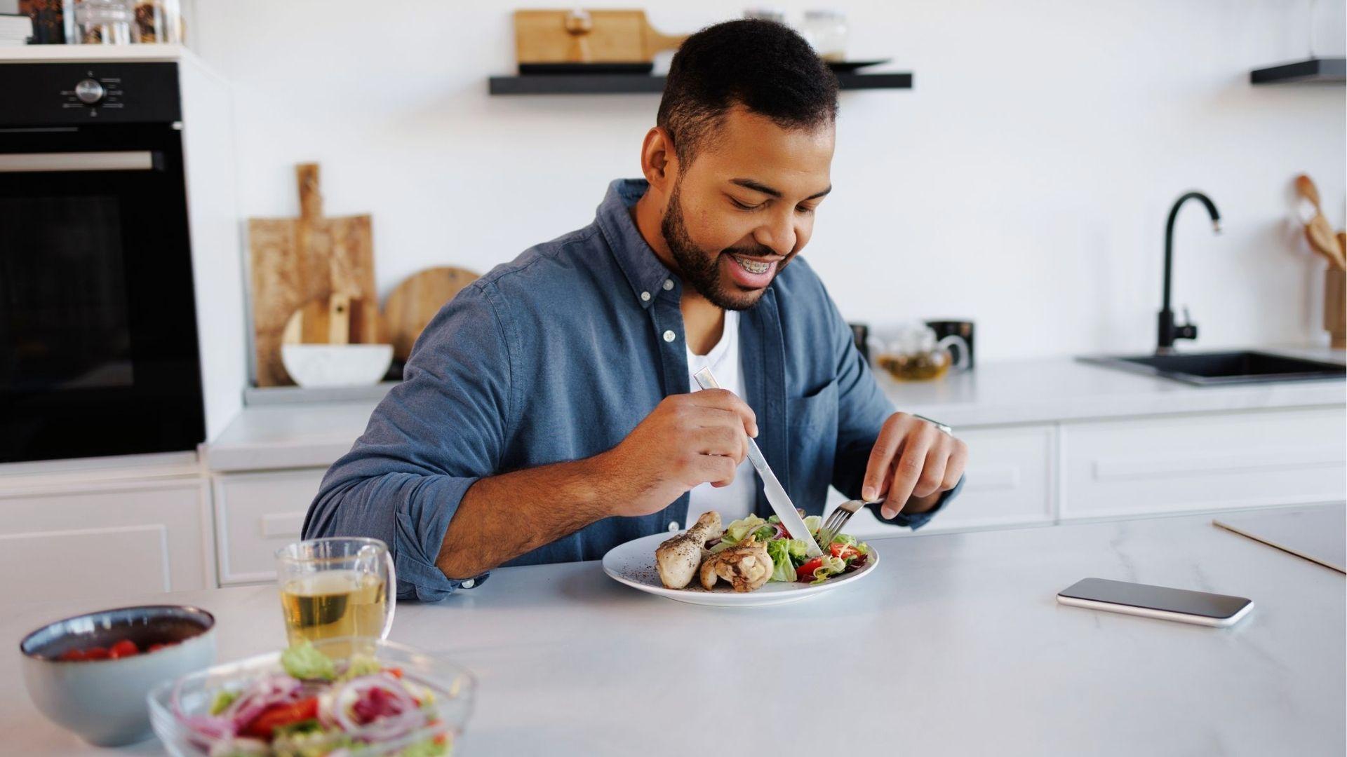 Smiling man eating nutritious meal in kitchen, showing how healthy food eases hangxiety