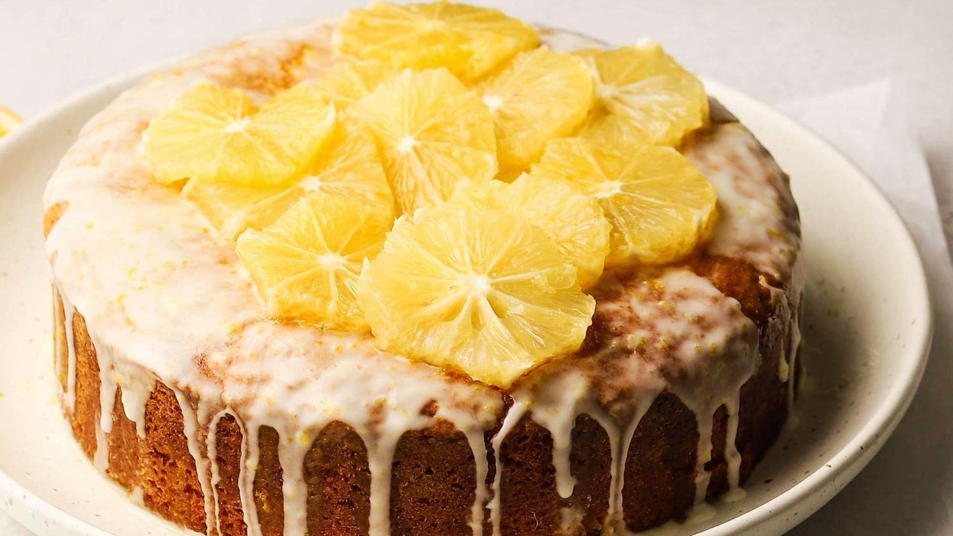 Glazed lemon cannabis cake topped with fresh lemon slices on white plate for easy baked edibles recipes