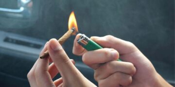 Lighting a rolled cannabis joint with a green lighter inside car before removing weed smell naturally