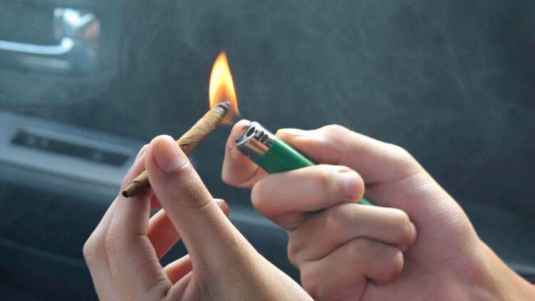 Lighting a rolled cannabis joint with a green lighter inside car before removing weed smell naturally
