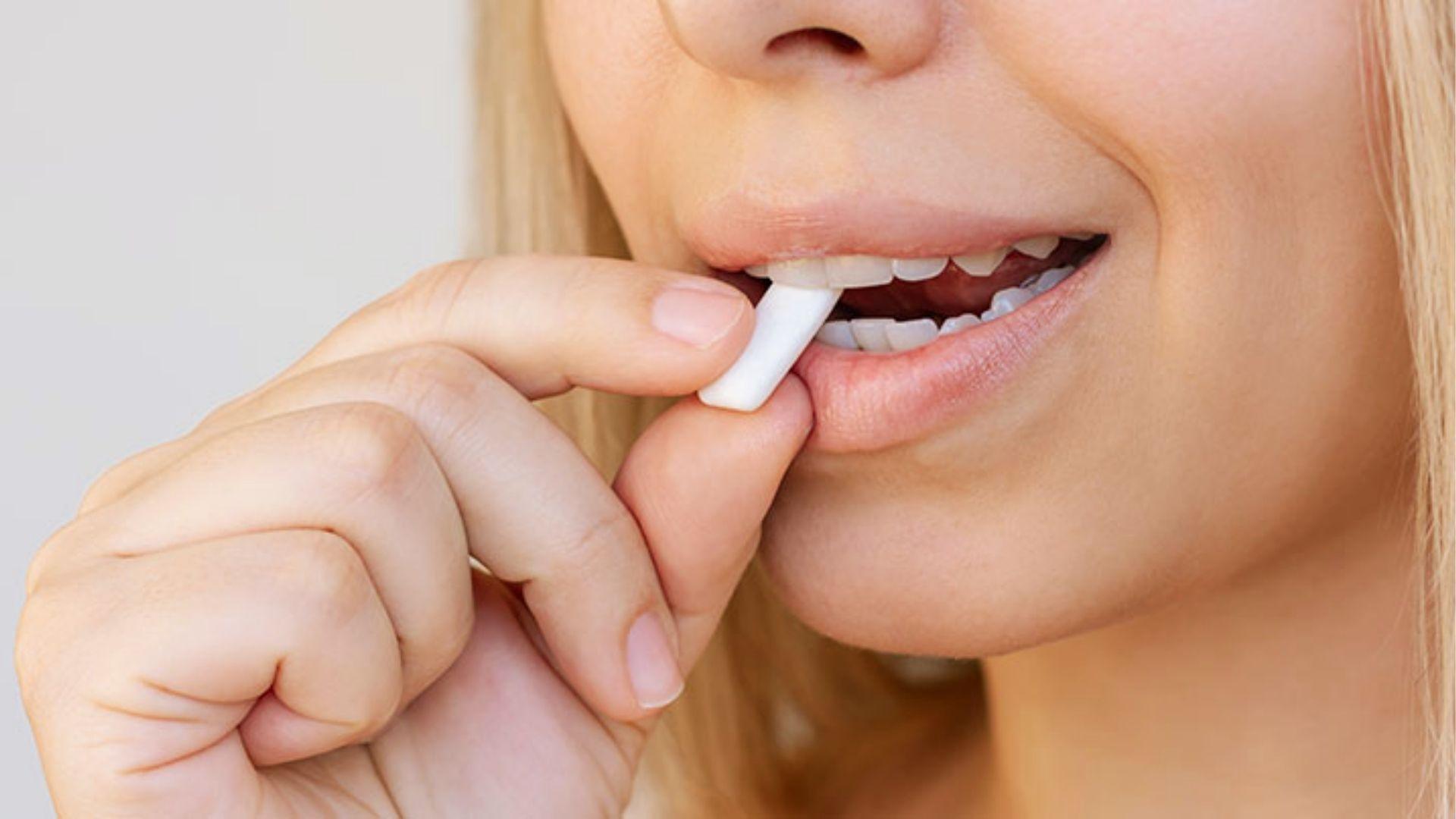 Close-up of woman chewing white gum to stimulate saliva and prevent cotton mouth dryness after consuming cannabis edibles