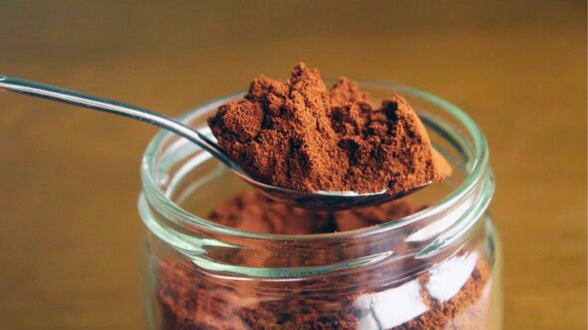 Spoonful of ground coffee in glass jar, a natural odor absorber for cars