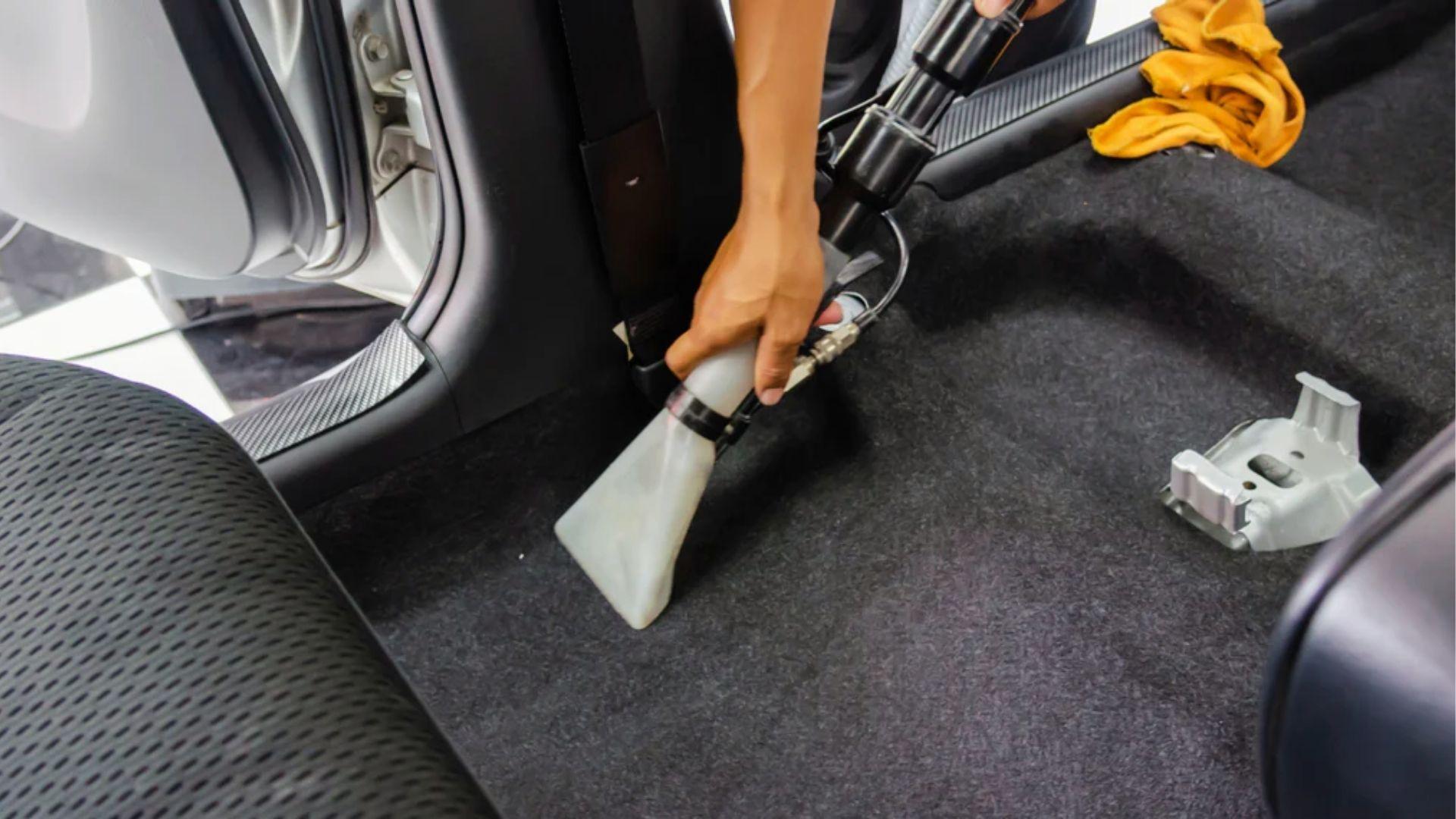 Deep cleaning car carpet with vacuum extractor to eliminate weed odor from upholstery fibers