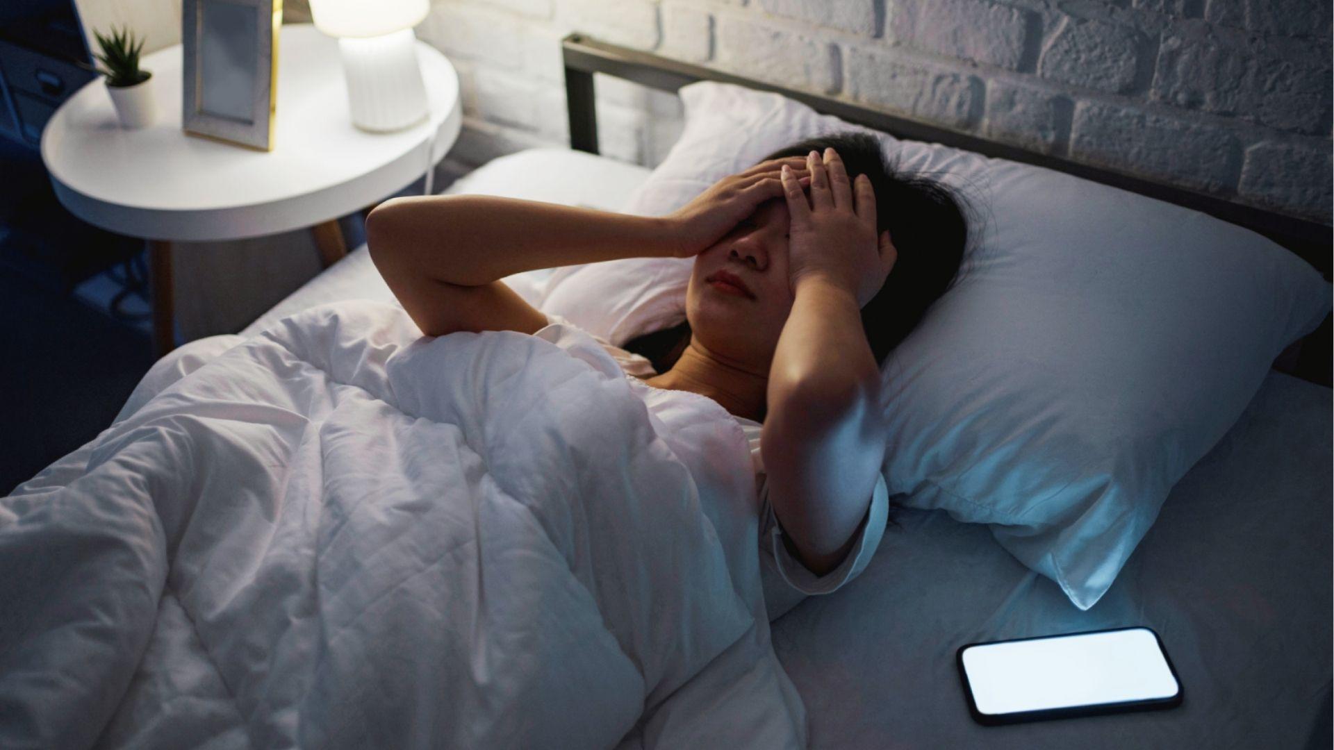 Woman lying in bed with hands on head suffering from weed hangover symptoms like headache and grogginess