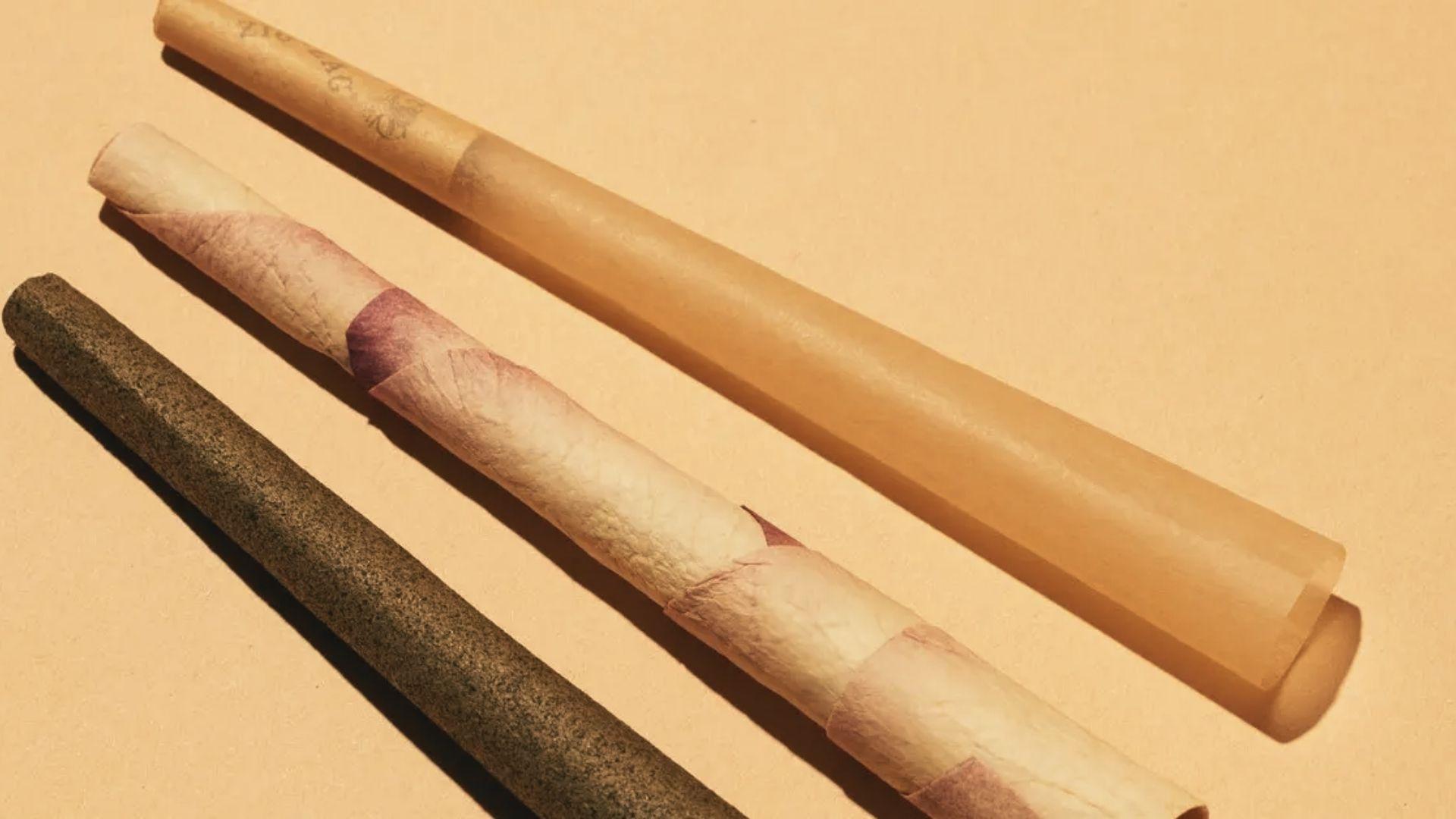 Three assorted cannabis pre-rolls including dark wrap, rose petal wrap, and clear cone arranged